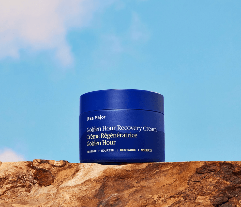 Blue jar of Ursa Major cream on rock, clear sky background.