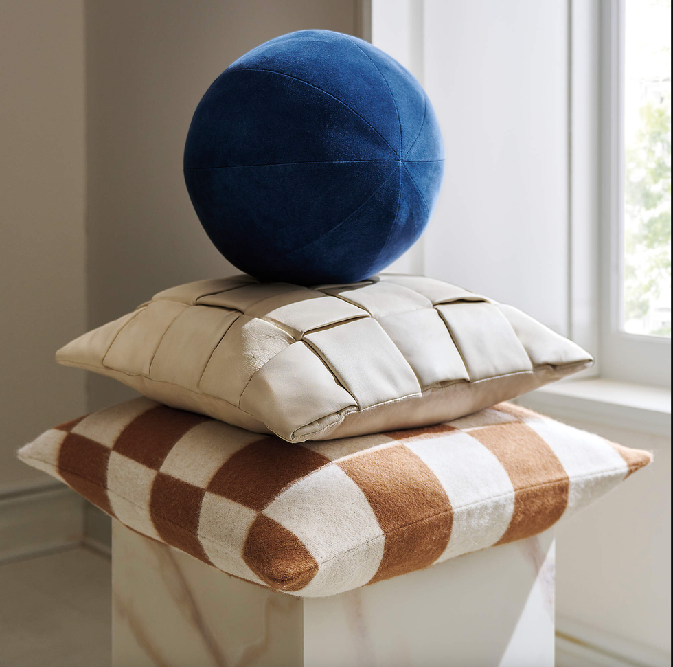 Blue sphere on beige and checkered pillows by a window.
