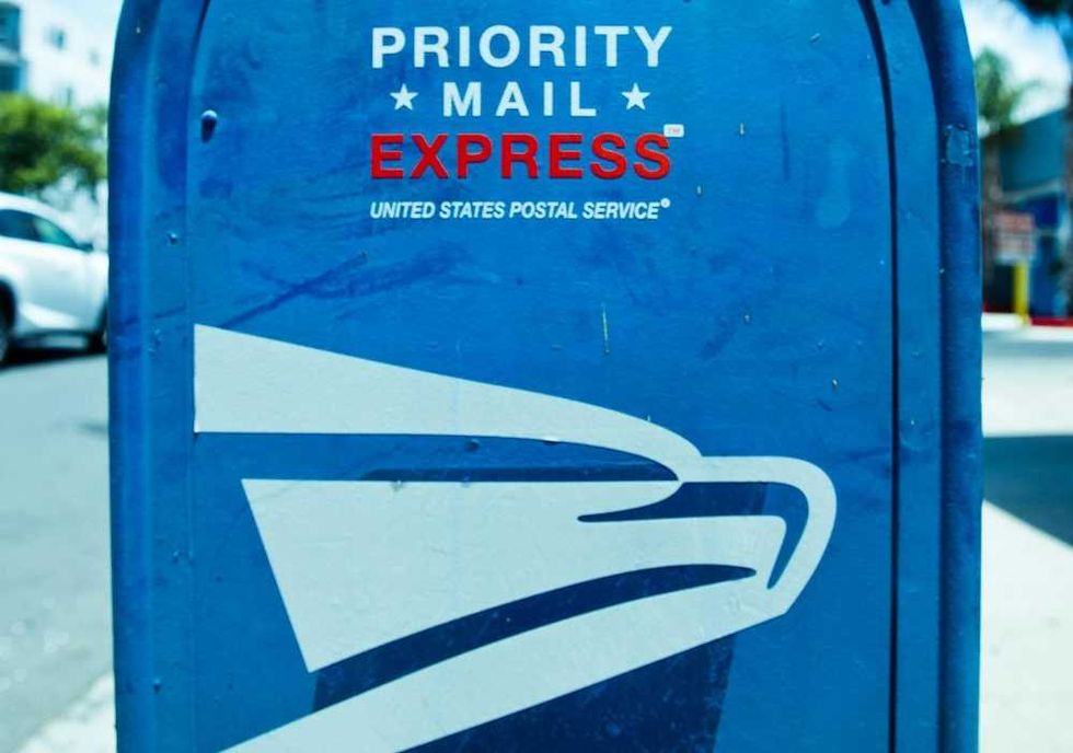 Blue USPS Priority Mail Express mailbox on a city street.