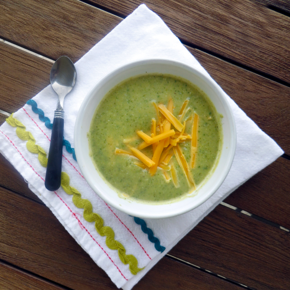 Bowl of broccoli cheese soup on a white cloth with spoon.