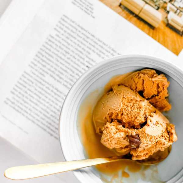 Bowl of caramel ice cream with spoon on a page of text.
