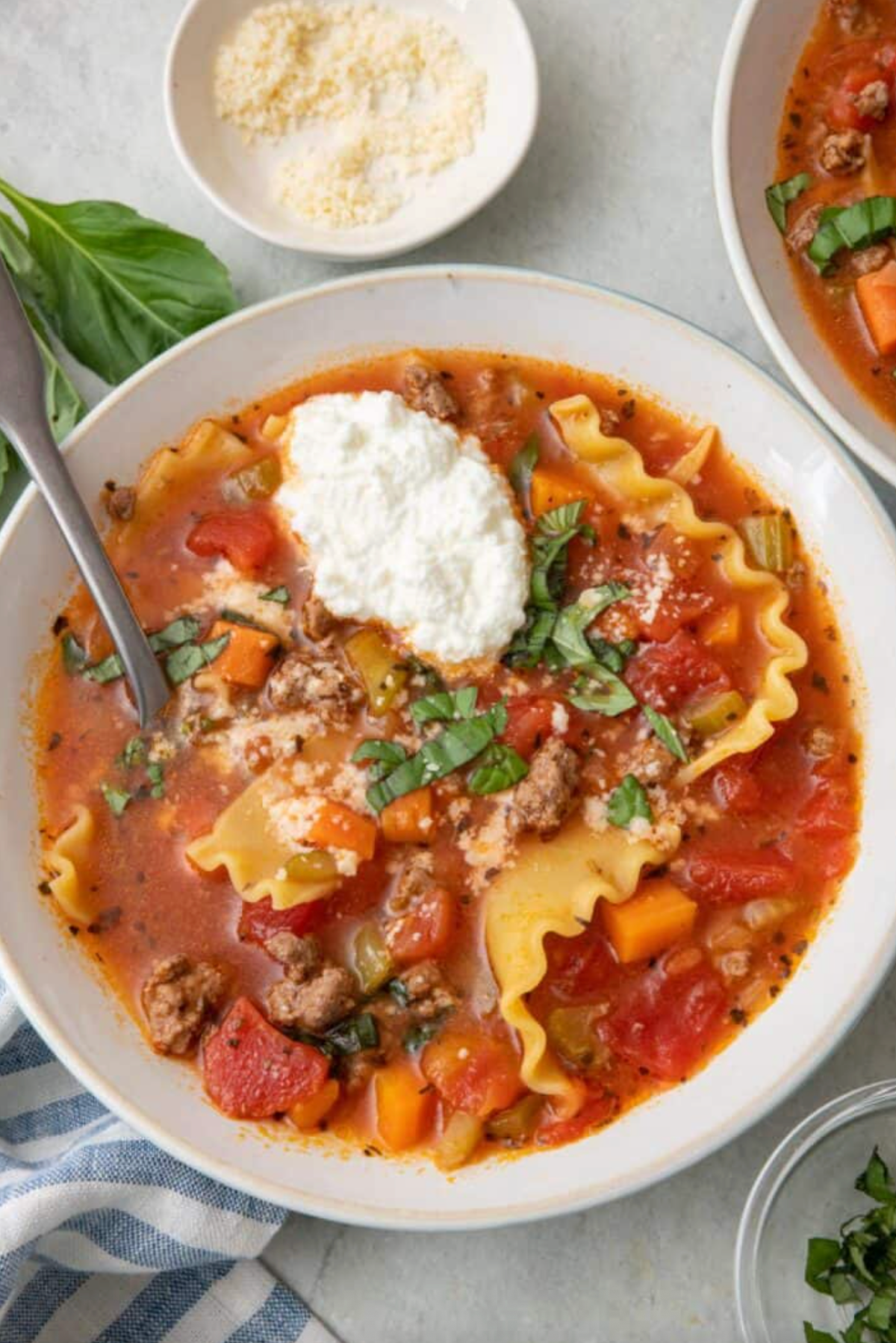 Bowl of lasagna soup with ricotta, basil, and vegetables.