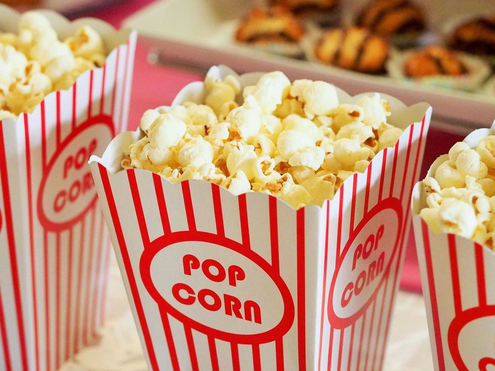 Boxes of popcorn with red stripes on a table, cookies blurred in the background.