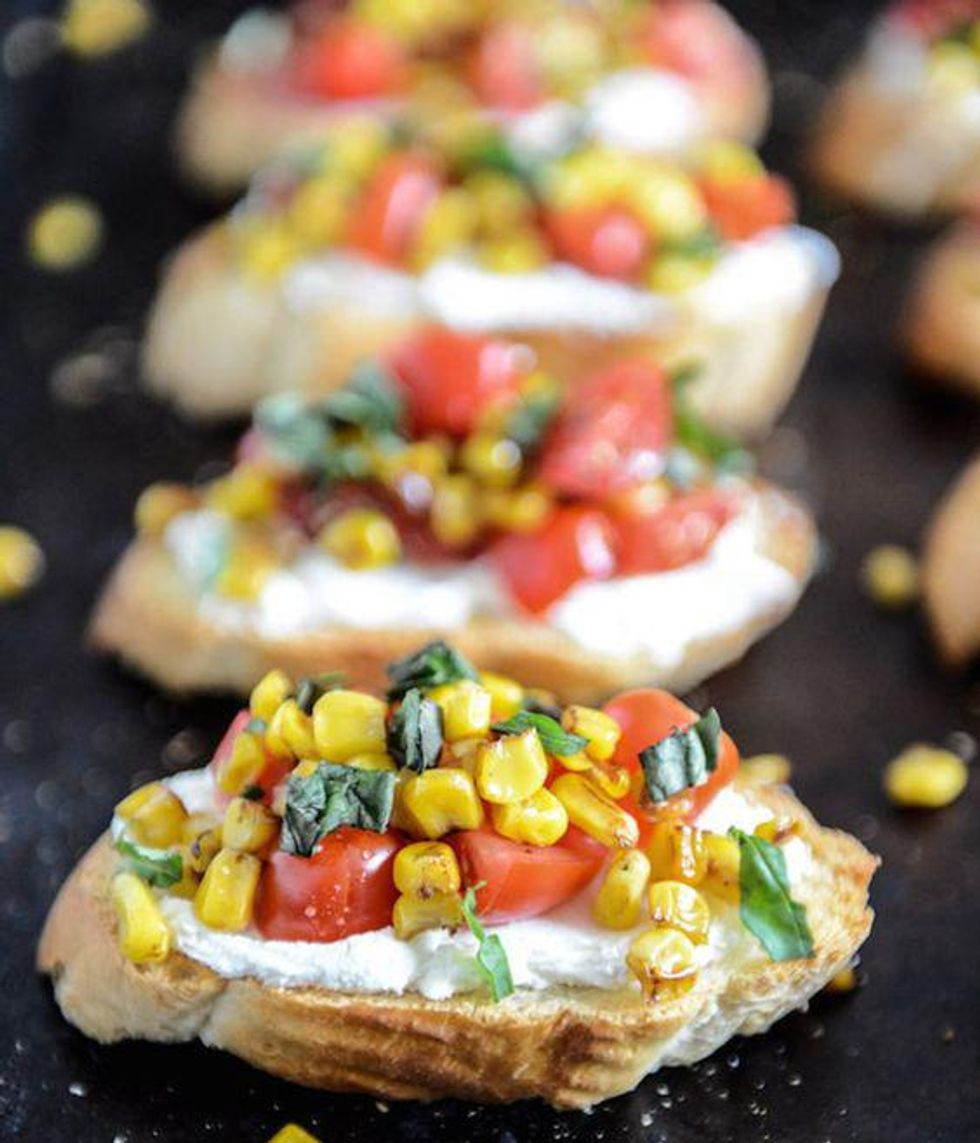 bread, cheese, grilled corn, tomato and basil on a black tray