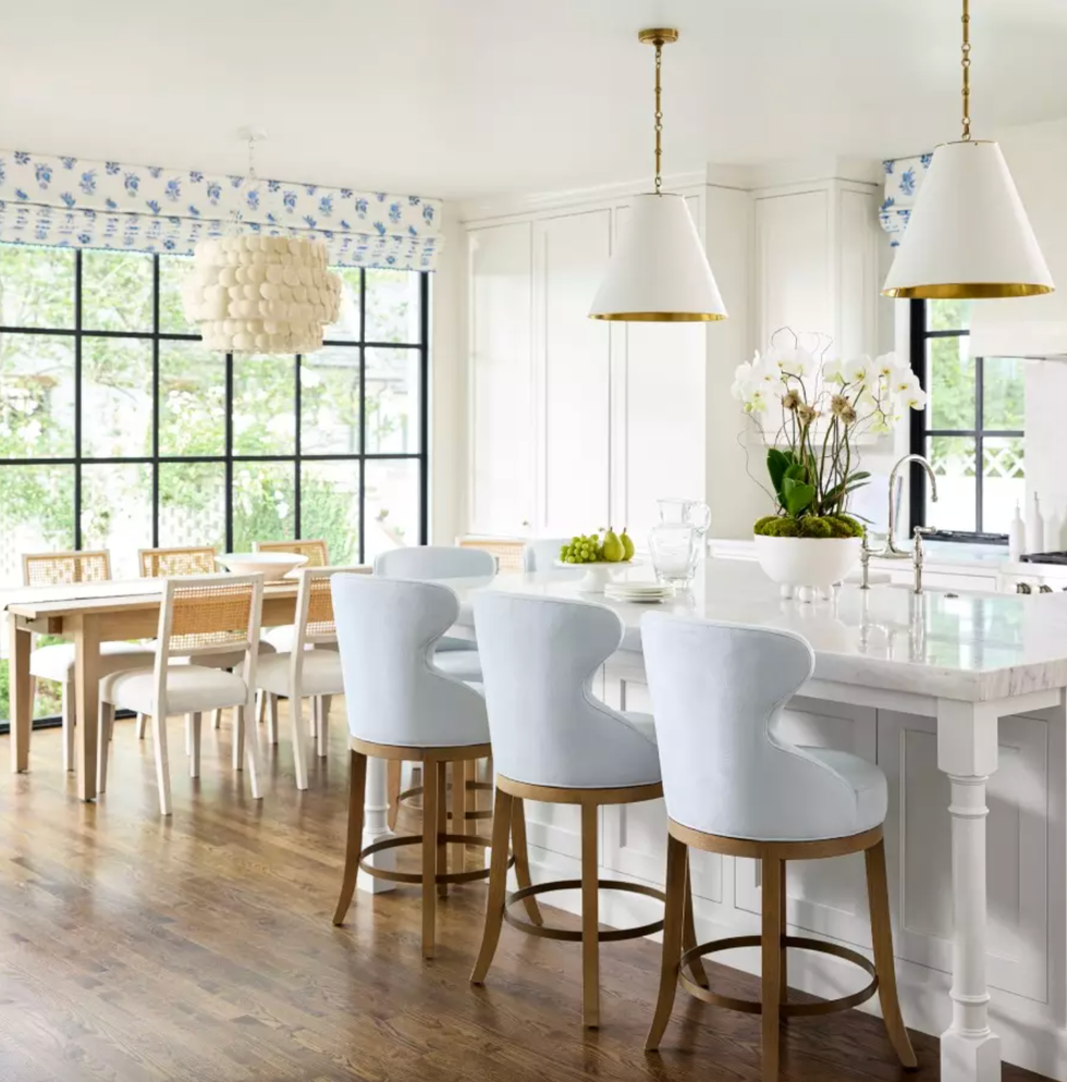 Bright kitchen with island seating, dining table, and large windows.