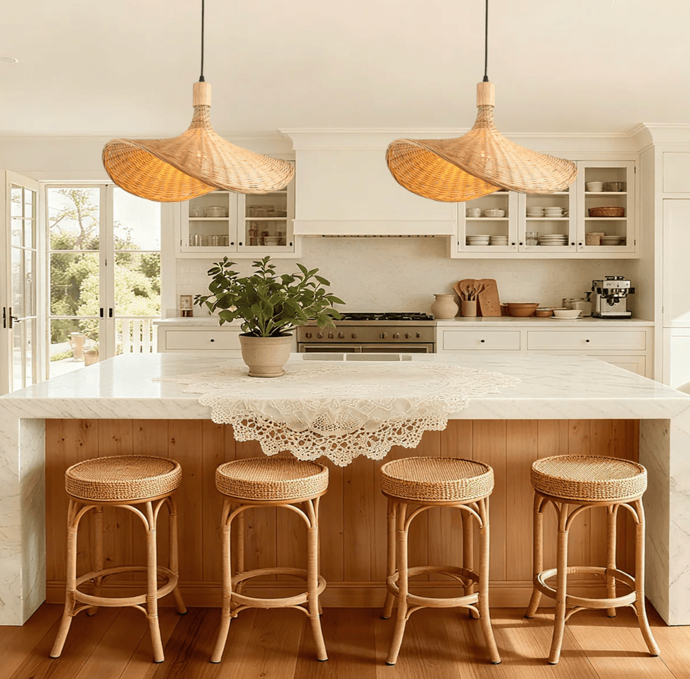 Bright kitchen with wicker lamps, marble island, rattan stools, and white cabinets.