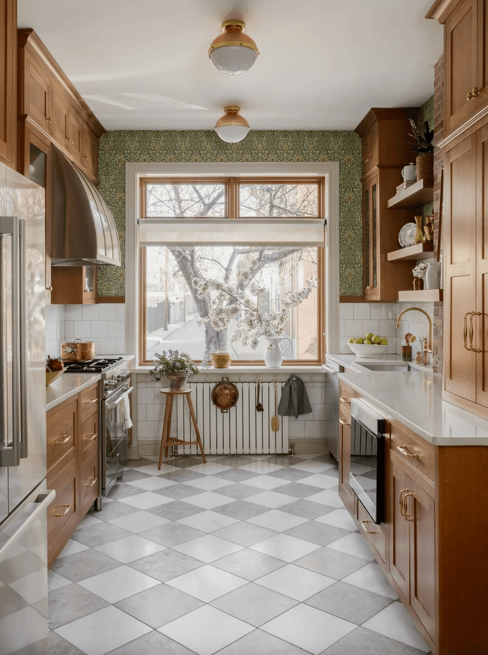 Bright kitchen with wooden cabinets, big window, checkerboard floor, and copper accents.