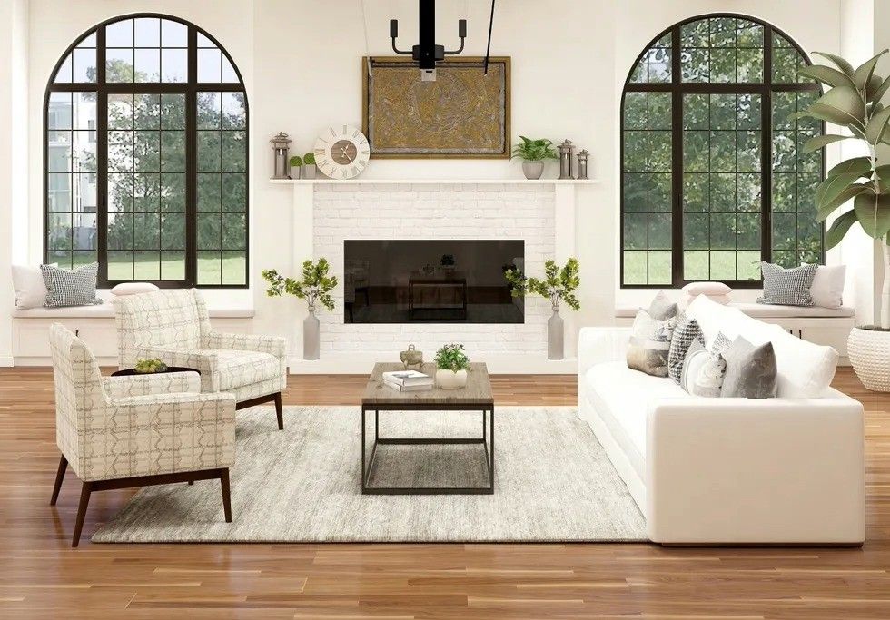 Bright living room with a white sofa, two chairs, and a fireplace under arched windows.