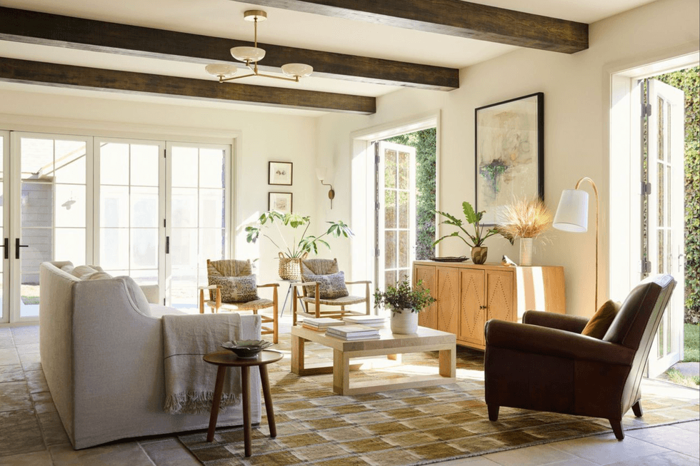 Bright living room with modern decor, wooden beams, and large windows.