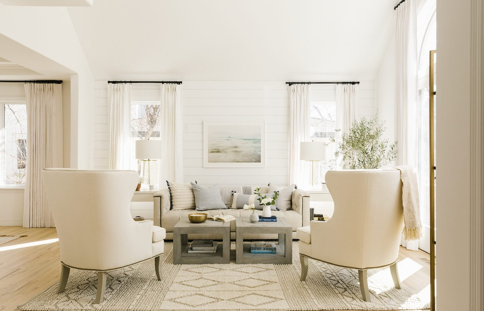 Bright living room with white chairs, sofa, and decor in neutral tones.