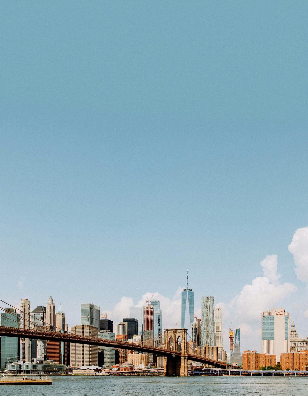 Brooklyn Bridge with Manhattan skyline under a clear blue sky.