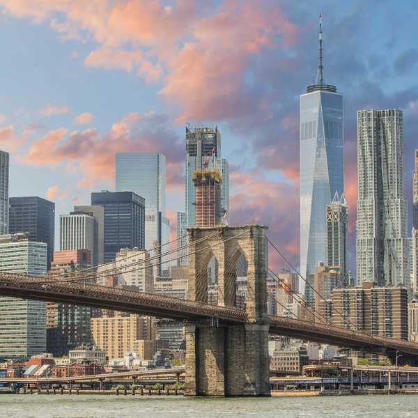 Brooklyn Bridge with New York City skyline at sunset.