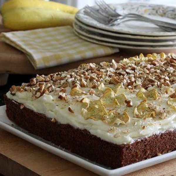 brown cake with white frosting and summer squash spirals on top