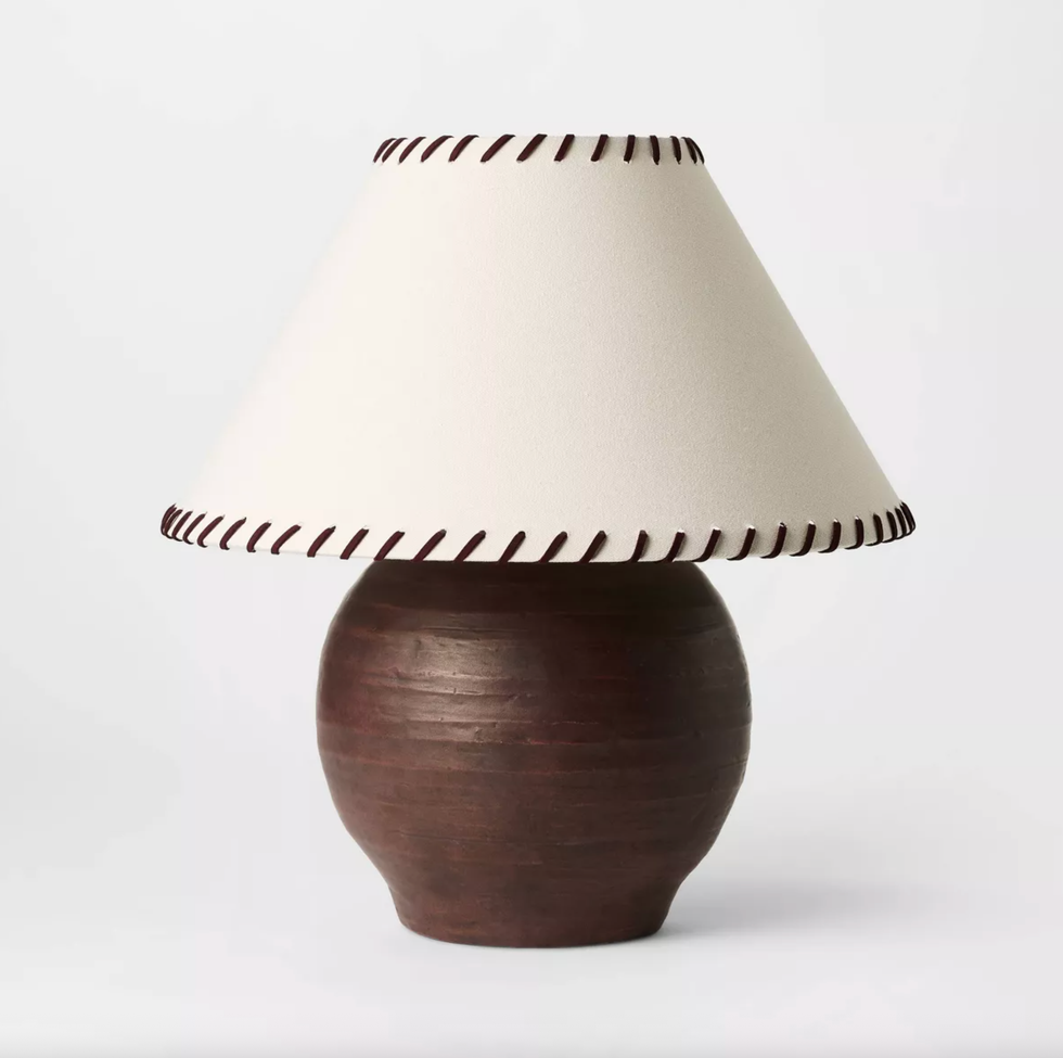 Brown ceramic lamp with a beige shade and dark stitched edges.