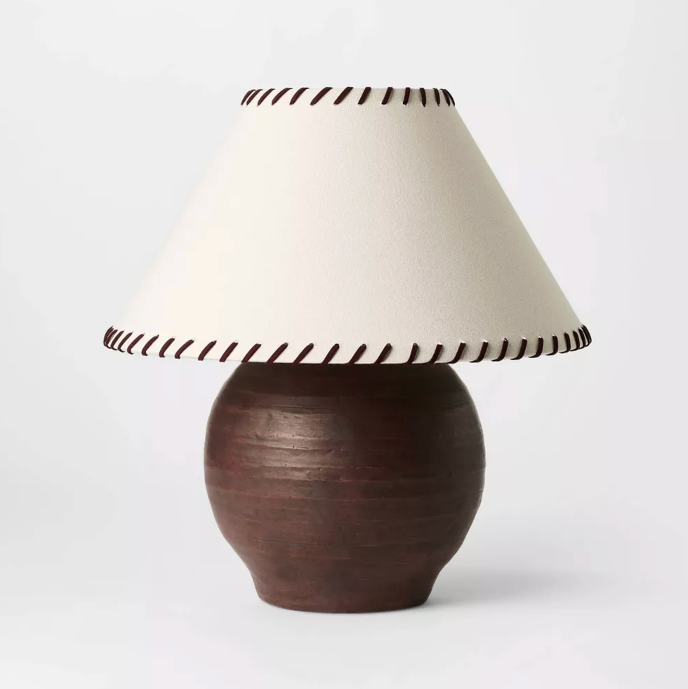 Brown ceramic lamp with a white shade, trimmed with dark stitching, on a white background.