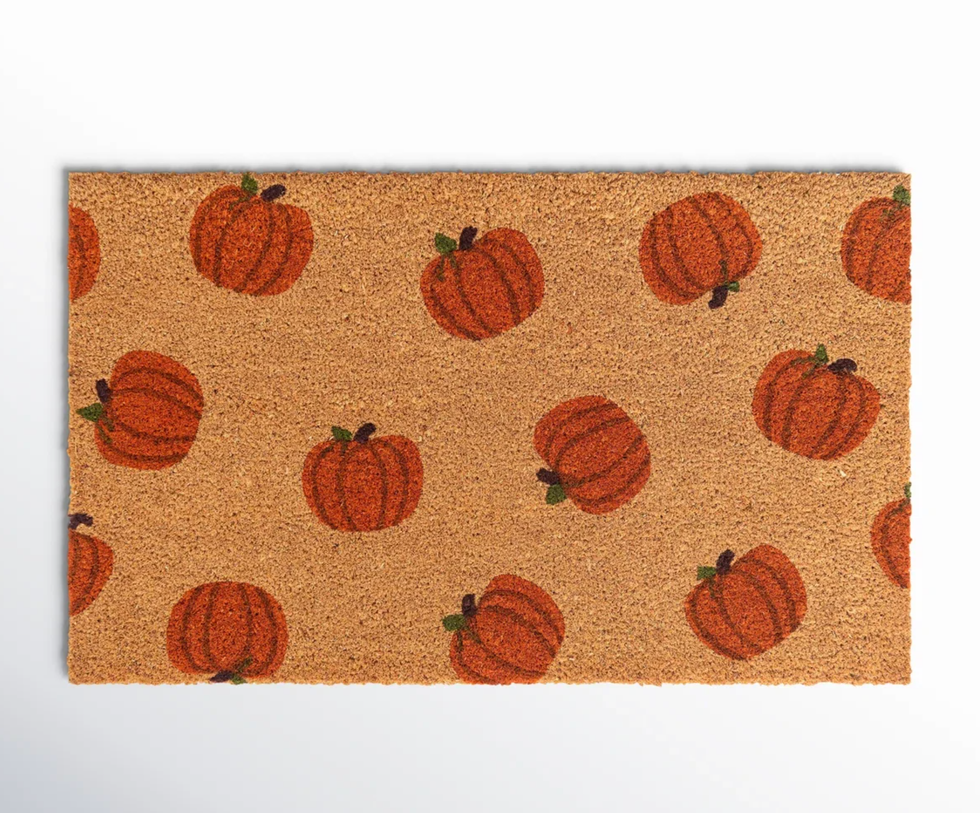 Brown doormat with orange pumpkin pattern.