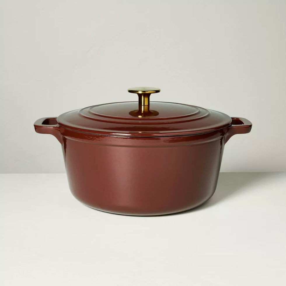 Brown Dutch oven with gold knob on a white surface.