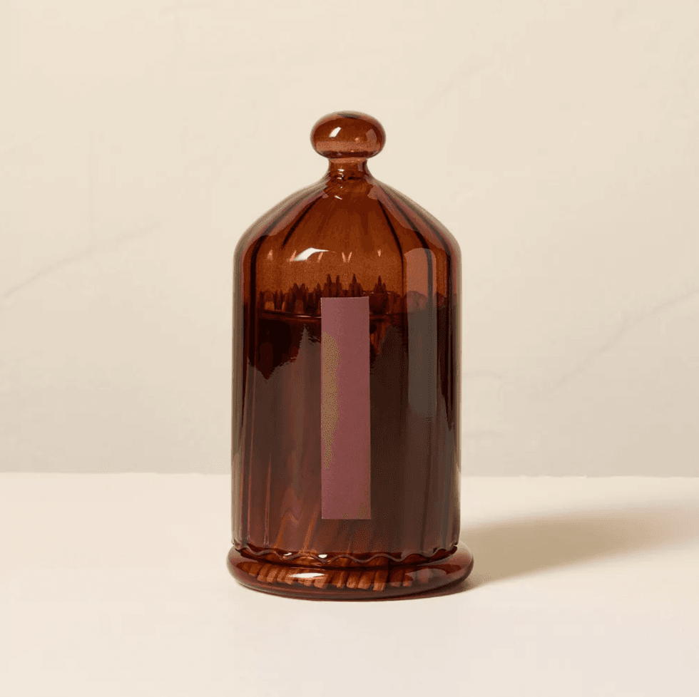 Brown glass dome with a handle, sitting on a white surface.