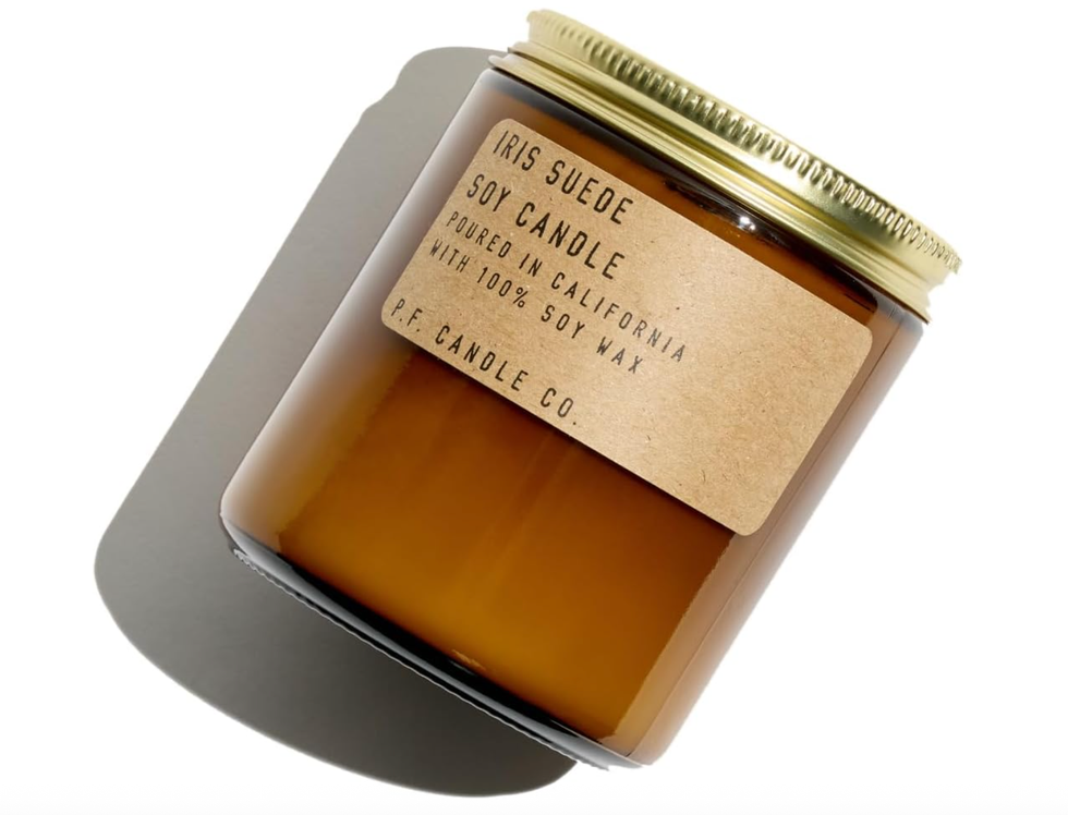 Brown glass jar labeled "Iris Suede Soy Candle" with a gold lid.
