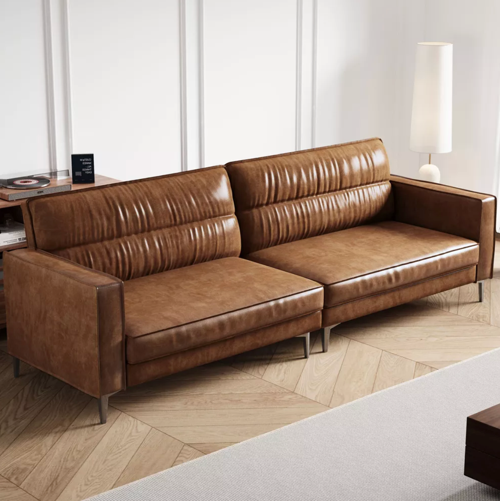 Brown leather sofa in a modern living room with a tall white lamp.