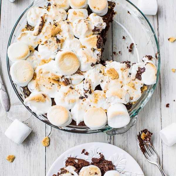 brownie pie with marshmallows on a white plate and a wooden table