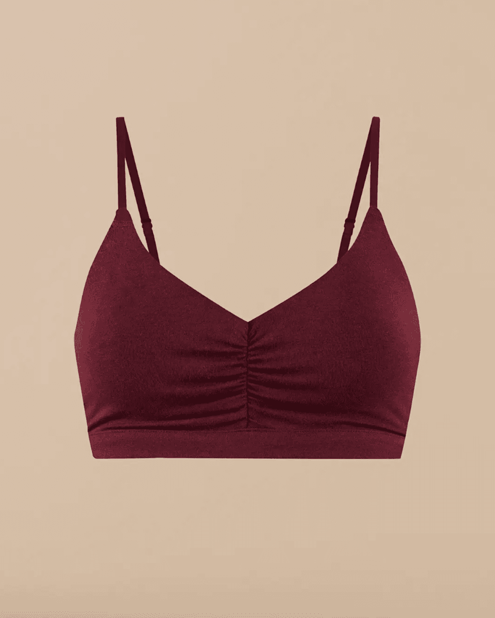 Burgundy bralette with thin straps on a beige background.