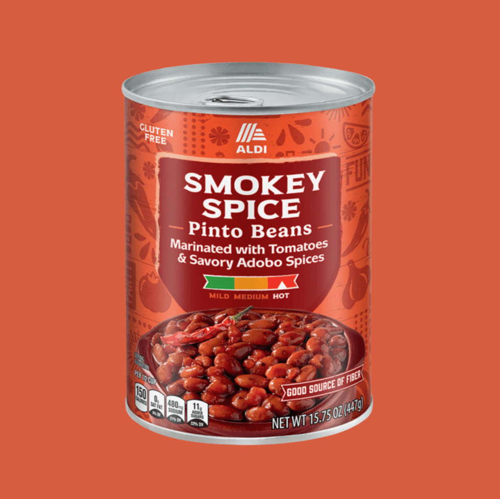 Can of Smokey Spice Pinto Beans with adobo spices on an orange background.