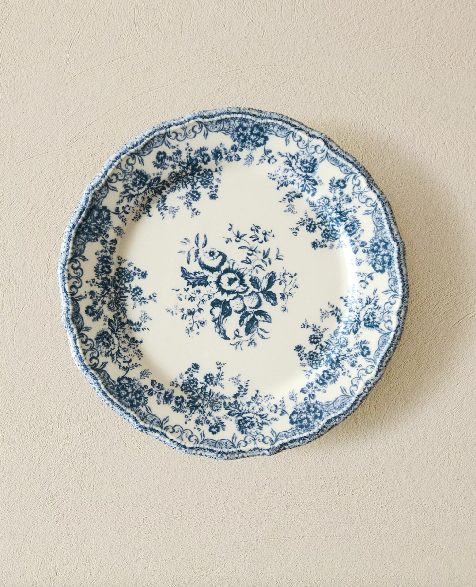 Ceramic plate with intricate blue floral pattern on a beige background.