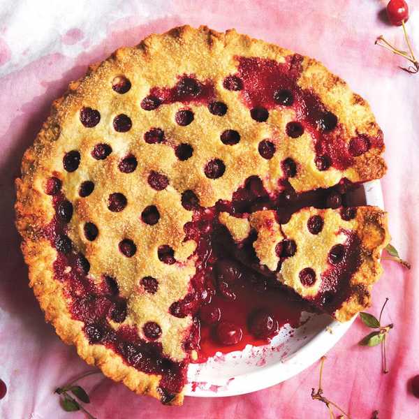 cherry pie with holes in the top sitting on a red table cloth