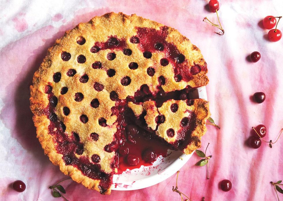 cherry pie with holes in the top sitting on a red table cloth