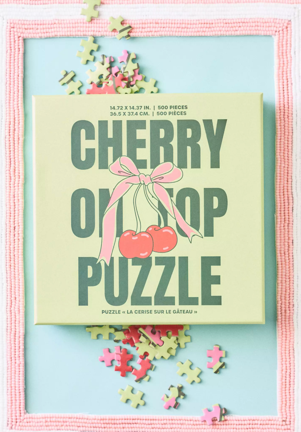 Cherry-themed puzzle box with scattered pieces on a pink-trimmed blue surface.