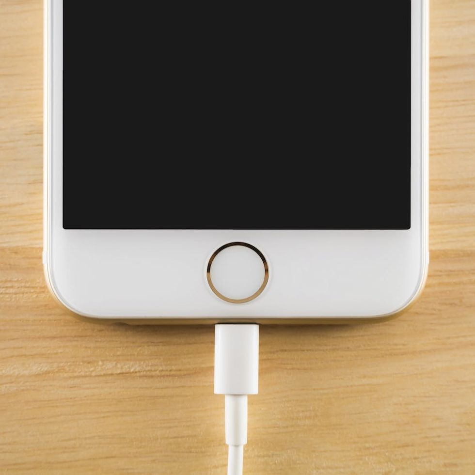Chiangrai, Thailand - July 28, 2016: Top view image of the Apple iPhone 6S charging with Lightning USB Cable on the wooden table on July 28, 2016 in Chiangrai Thailand.