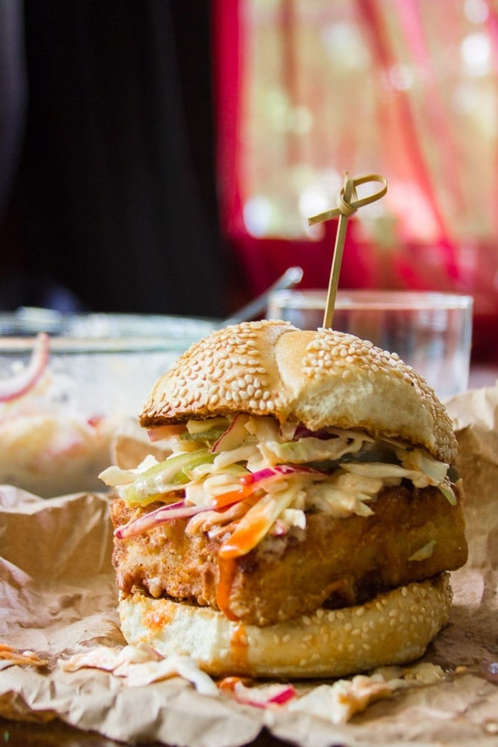 "Chicken" Fried Tofu Sandwich with Spicy Buffalo Slaw with Drinking Glass and Mixing Bowl in the Background