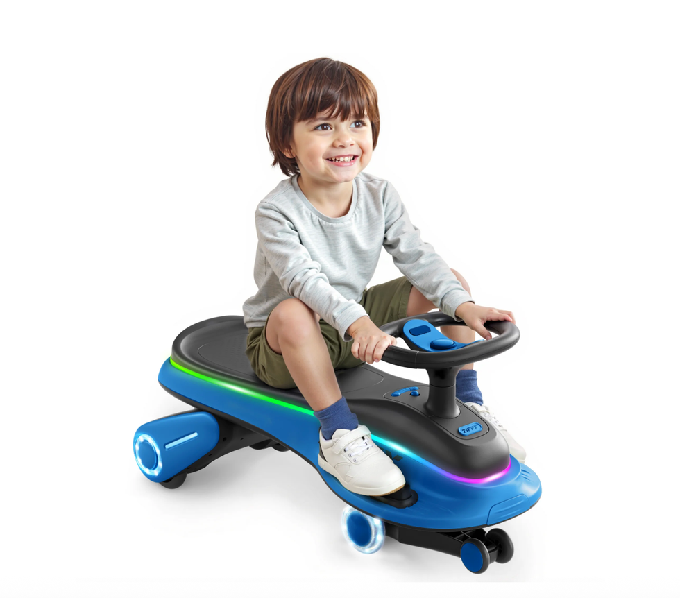 Child smiling on a blue ride-on toy with glowing lights, wearing a gray shirt and olive shorts.