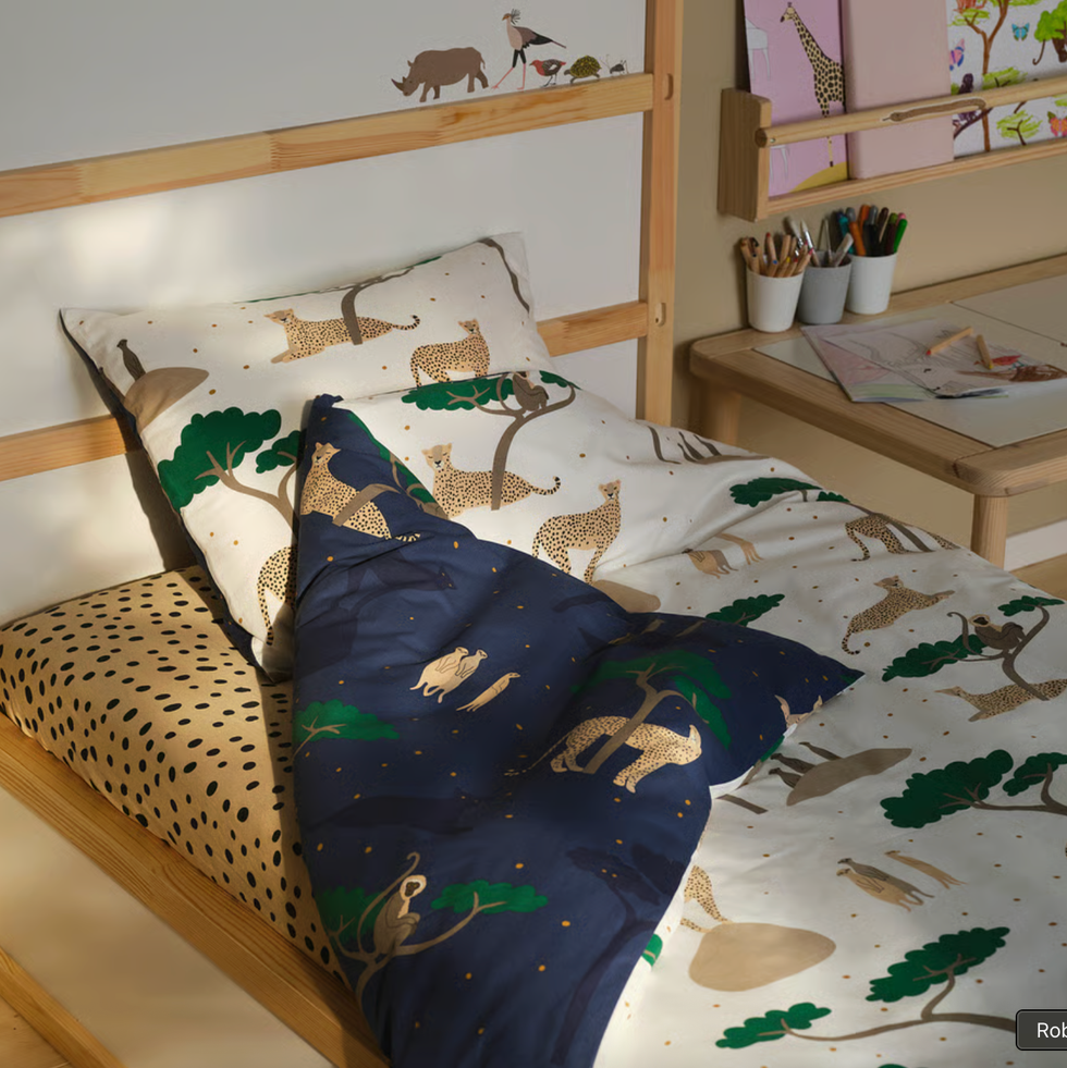 Children's bed with animal-themed bedding and a small desk with art supplies.