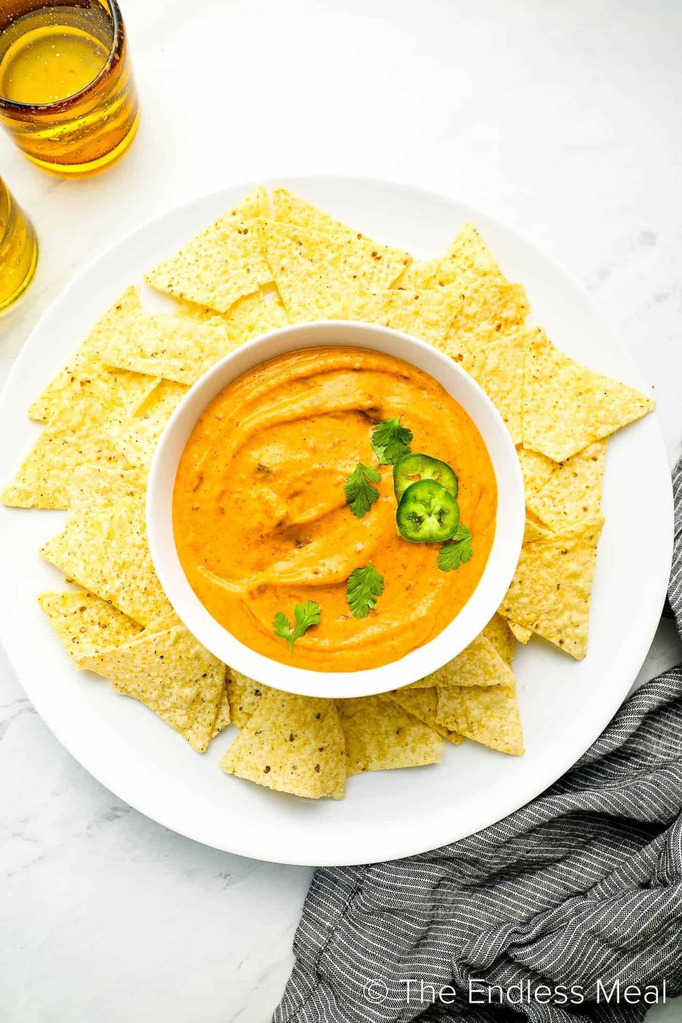 Chili cheese dip is in a bowl surrounded by chips.