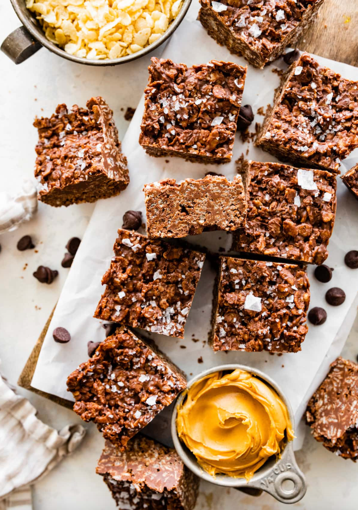 Chocolate crispy bars with sea salt, surrounded by peanut butter and cereal.