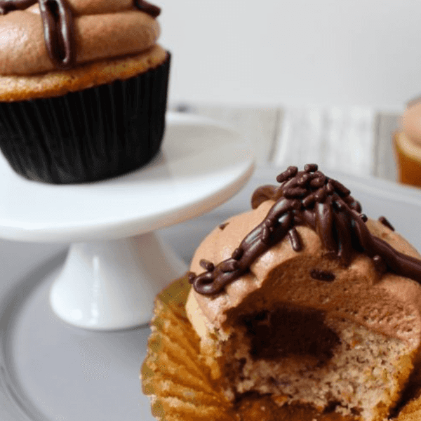 Chocolate cupcakes on a stand, one with a bite taken out.