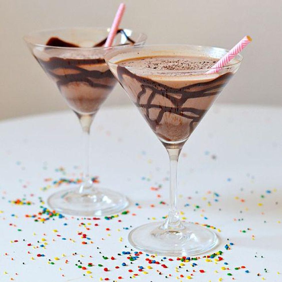 Chocolate martini in a glass with pink paper straws and rainbow sprinkles all around