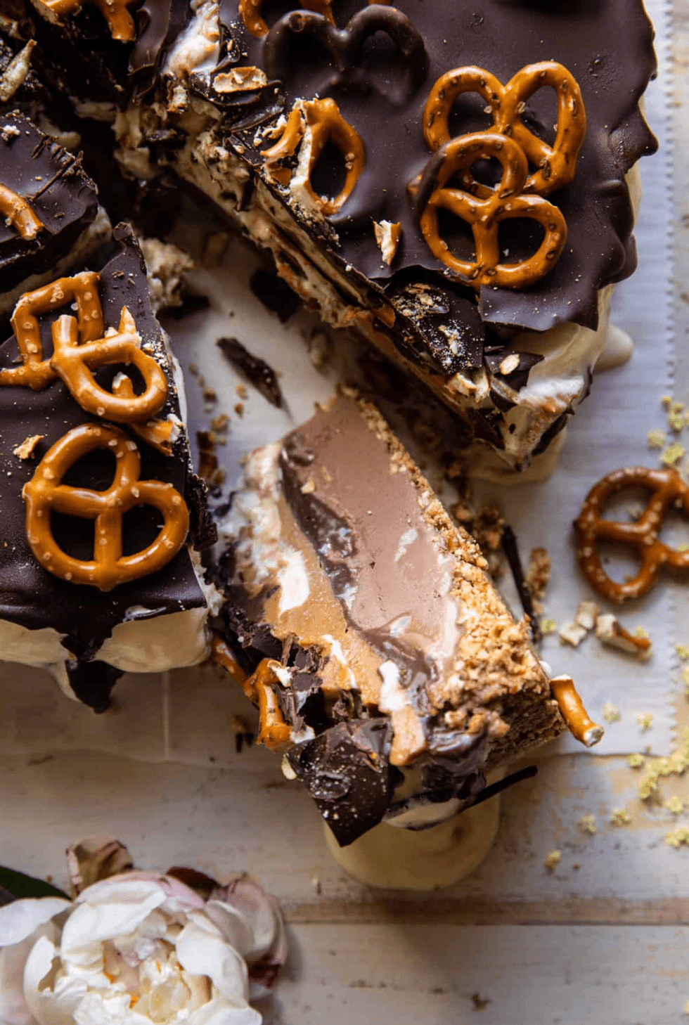 Chocolate peanut butter pie topped with pretzels on a wooden surface.