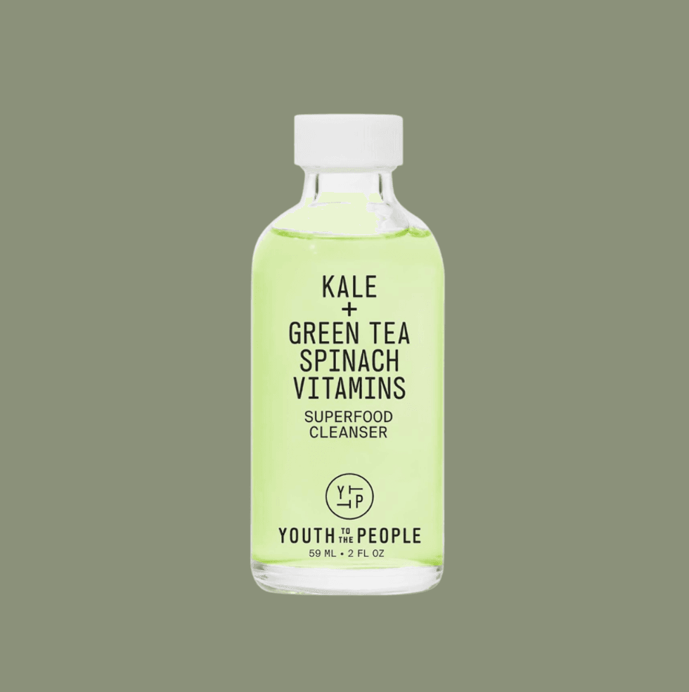 Clear bottle of green superfood cleanser on olive background.