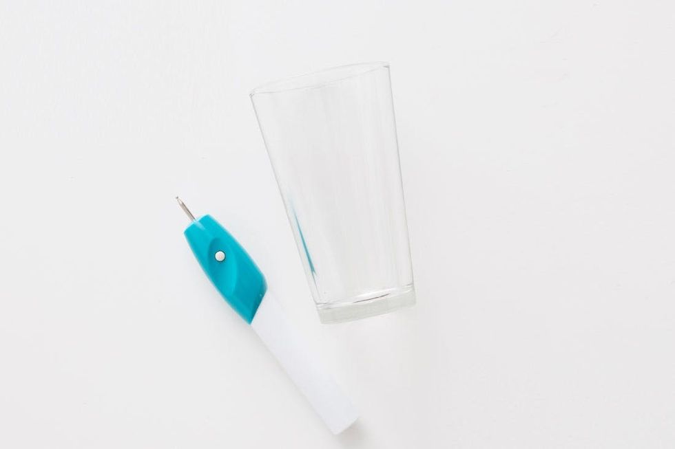 Clear glass and a blue utility knife on a white surface.