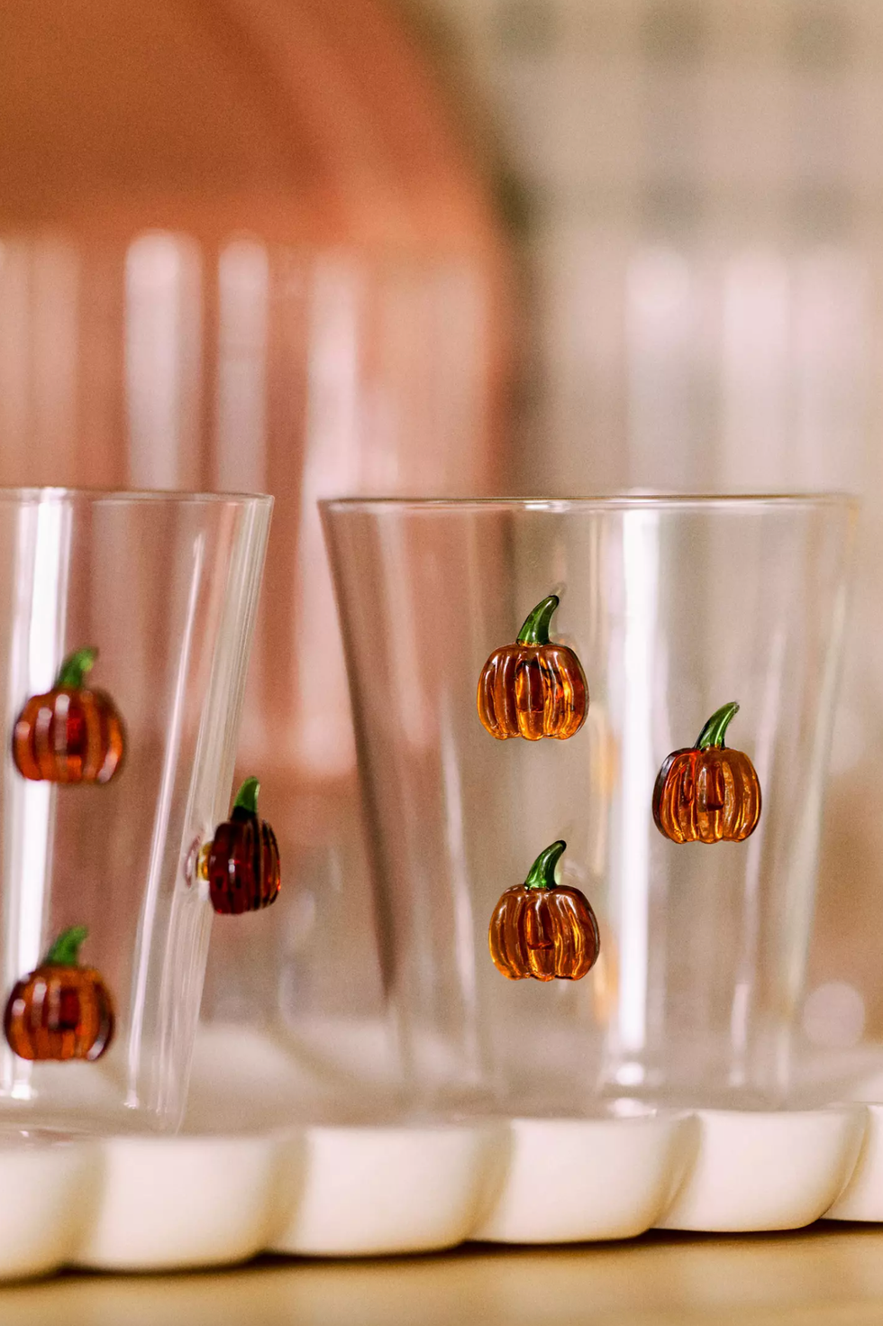 Clear glasses with mini pumpkin designs on a white tray.