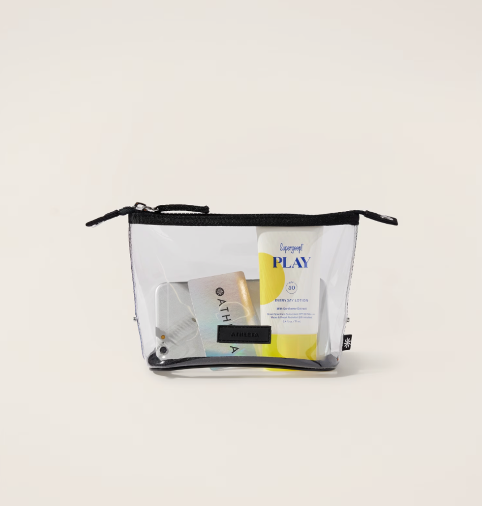 Clear travel pouch with sunscreen and various skincare items inside.