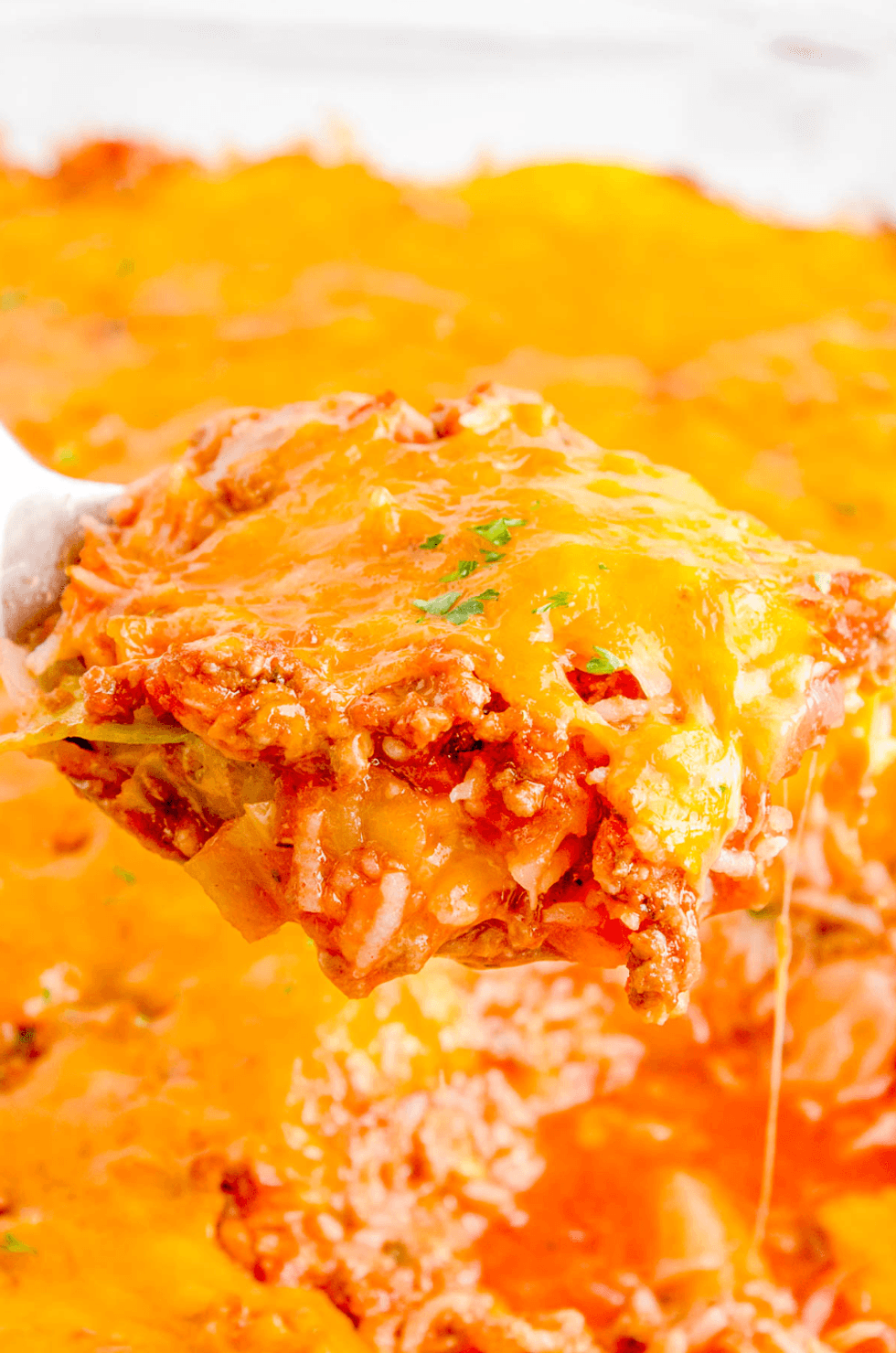 Close-up of cheesy casserole with meat and rice being served.
