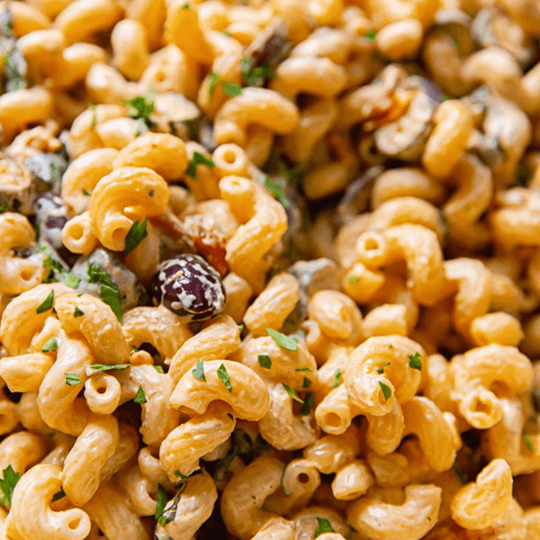 Close-up of creamy macaroni salad with herbs and vegetables.