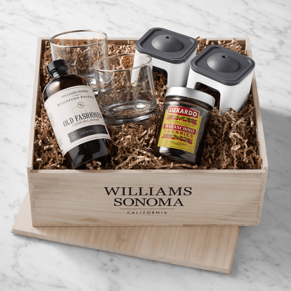 Cocktail gift set with mixer, glasses, cherries, and ice molds in a wooden box.