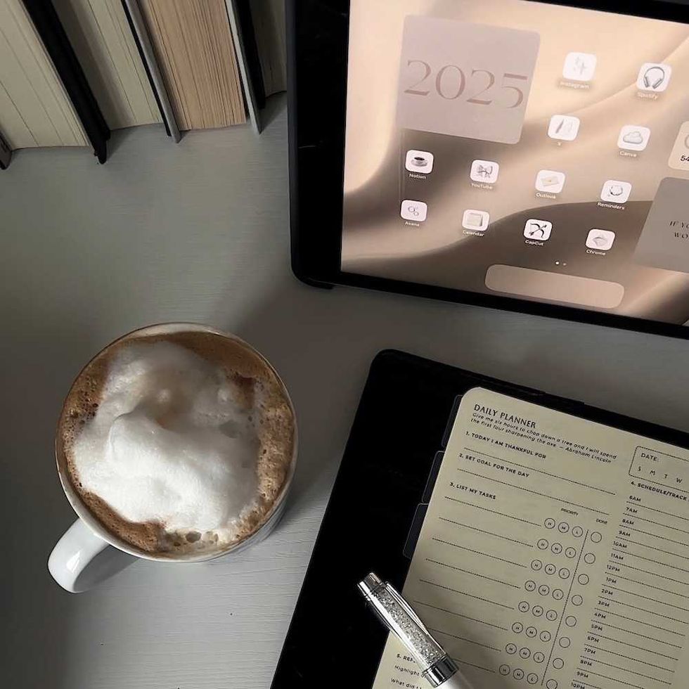 Coffee, digital planner showing 2025, open notebook on desk with books.
