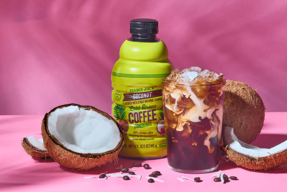 Cold brew coffee, coconuts, and coffee concentrate bottle on a pink background.