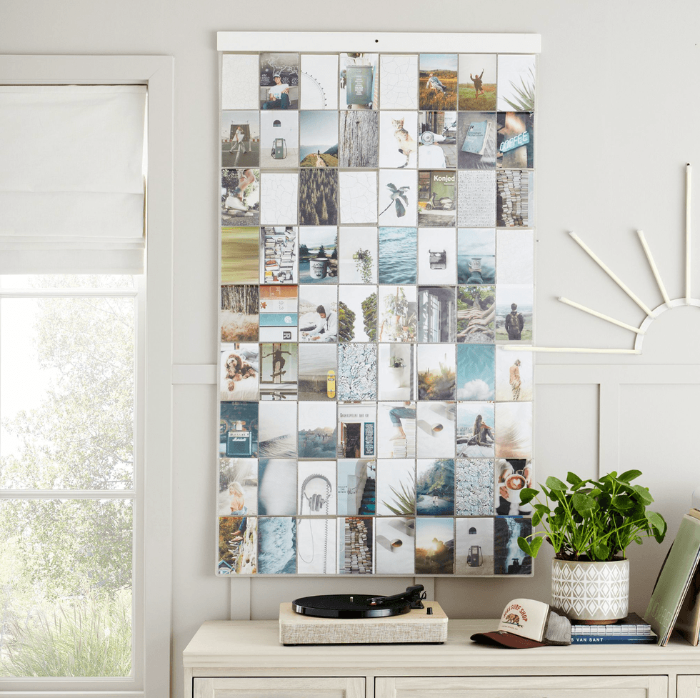 Collage of small photos on wall above a turntable and a plant on a white cabinet.